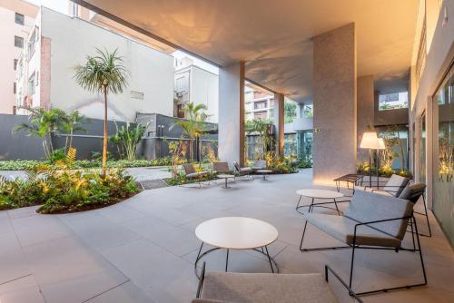 a lobby with tables and chairs and palm trees at GO Rio Branco by LikeHome in Porto Alegre
