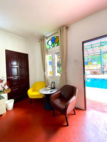 a living room with a table and a yellow chair at Bayu Bayu Hotel by Soft Loft in Tanjung Bungah