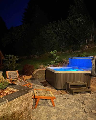 - un bain à remous avec deux chaises et une table dans l'établissement Chalet Le Montagnard SPA & SAUNA - Lits faits - Serviettes - Peignoirs - Ménage inclus, à Rochesson