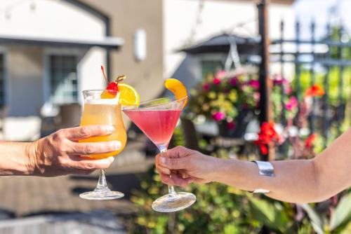 two people holding up two cocktails in their hands at Inn on Prince Hotel and Conference Centre Truro in Truro