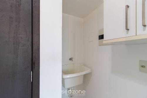 a white bathroom with a sink and a cabinet at SPT - Studios Convenientes em Blumenau/SC in Blumenau