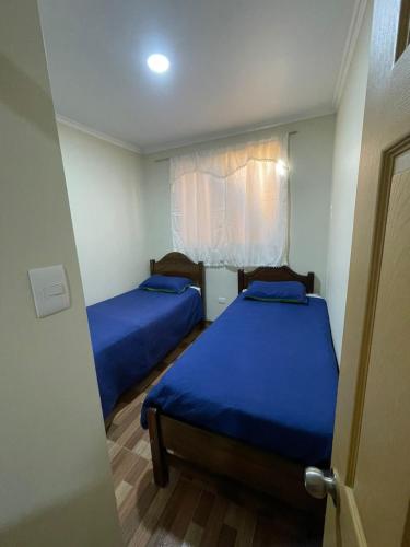 two beds in a small room with blue sheets at Apartamentos Lourdes in Antofagasta