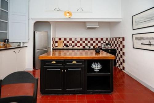 une cuisine avec un îlot noir au milieu dans l'établissement Hôtel Particulier Aix, à Aix-en-Provence