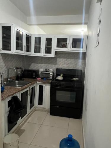 a kitchen with a black stove and a sink at Habitación económica in Santiago de los Caballeros