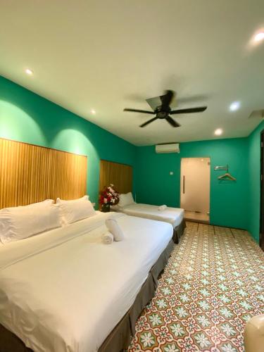 two beds in a room with a ceiling fan at Bayu Bayu Hotel by Soft Loft in Tanjung Bungah