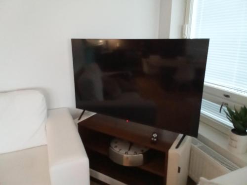 a flat screen tv sitting on a stand next to a couch at TAMPERE PENTHOUSE-tasokas moderni kaupunki huoneisto huipulla -ISO JACUZZI omalla KATTOTERASSILLA - AURINKOTUOLIT ja Aurinko odottaa Sinua - huikea maisema- - 10 HLÖ - free parking in Tampere