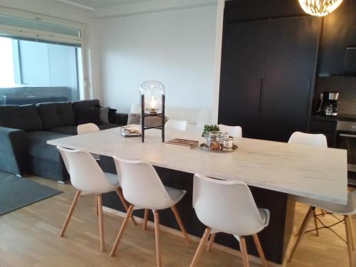 a dining room with a large white table and white chairs at TAMPERE PENTHOUSE-tasokas moderni kaupunki huoneisto huipulla -ISO JACUZZI omalla KATTOTERASSILLA - AURINKOTUOLIT ja Aurinko odottaa Sinua - huikea maisema- - 10 HLÖ - free parking in Tampere
