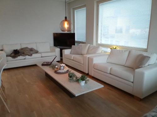 a living room with two white couches and a table at TAMPERE PENTHOUSE-tasokas moderni kaupunki huoneisto huipulla -ISO JACUZZI omalla KATTOTERASSILLA - AURINKOTUOLIT ja Aurinko odottaa Sinua - huikea maisema- - 10 HLÖ - free parking in Tampere