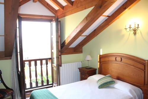 a bedroom with a bed and a large window at Posada La Cabaña De Salmon in Santillana del Mar