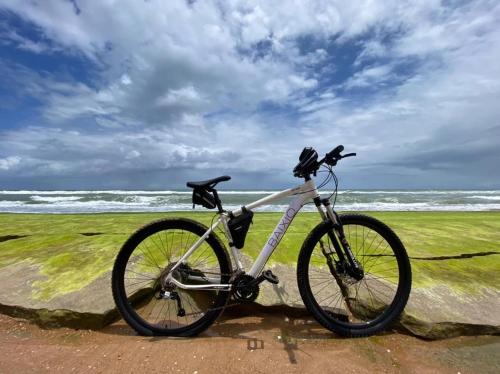 a bike parked on the beach near the ocean at Apartamento em condomínio com passeio incluso in Baixio