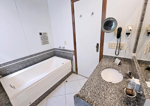a bathroom with a tub and a toilet and a phone at Riale Imperial Flamengo in Rio de Janeiro