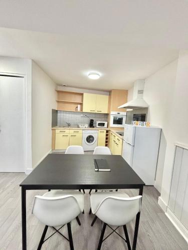 une cuisine avec une table noire et des appareils électroménagers blancs dans l'établissement appartement confort, à Gray