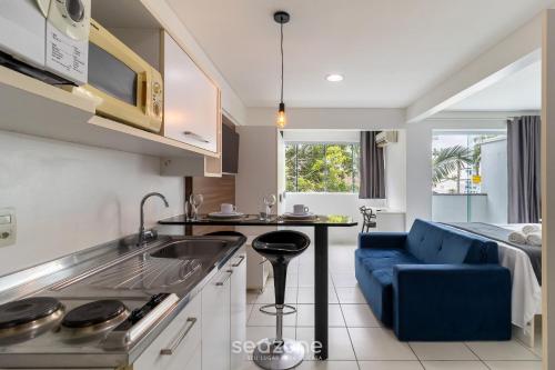 a kitchen with a sink and a couch in a room at SPT - Studios Convenientes em Blumenau/SC in Blumenau