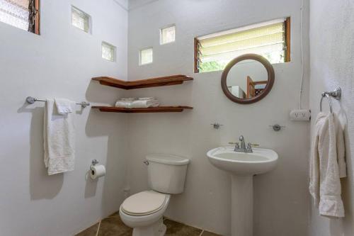 a white bathroom with a toilet and a sink at Surfsidelodge in Cabo Matapalo