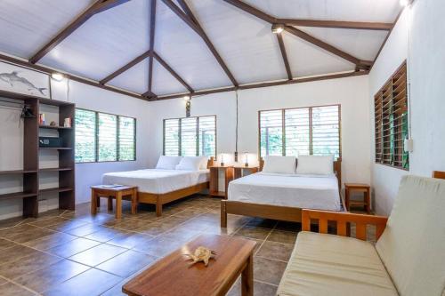 a bedroom with two beds and a couch and a table at Surfsidelodge in Cabo Matapalo