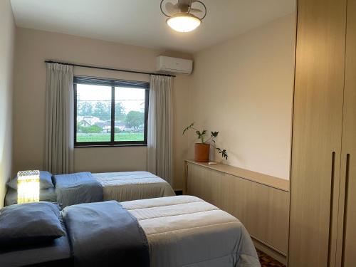 a bedroom with two beds and a window at Apartamento tropical no centro de Pomerode in Pomerode
