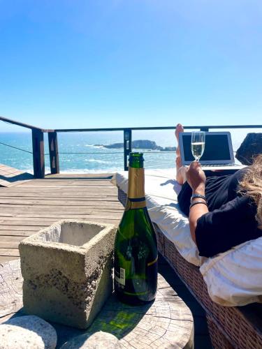 a woman laying on a bed with a bottle of wine and a glass at Mirada al Mar in Matanzas