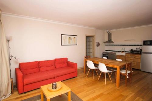 un salon avec un canapé rouge et une table dans l'établissement Appartement du XVIIè siècle, hypercentre 2 chambres, à La Rochelle