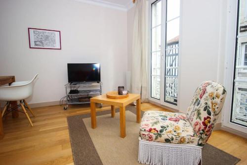 - un salon avec une chaise, une table et une télévision dans l'établissement Appartement du XVIIè siècle, hypercentre 2 chambres, à La Rochelle
