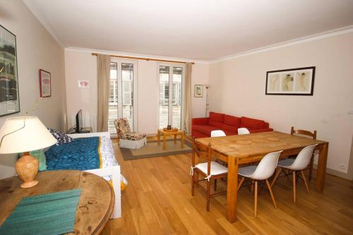 un salon avec une table et un canapé rouge dans l'établissement Appartement du XVIIè siècle, hypercentre 2 chambres, à La Rochelle