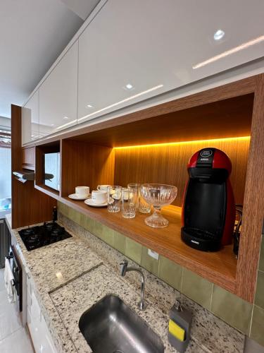 a kitchen with a toaster and glasses on a shelf at Apartamento Concierge Sensacional in Marabá