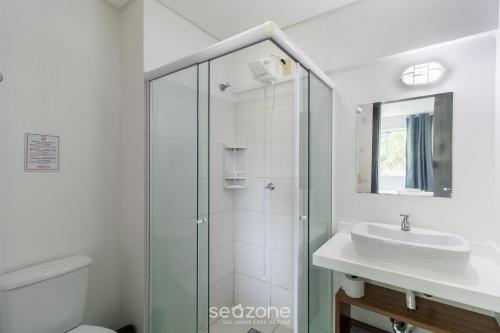 a bathroom with a glass shower and a sink at SPT - Studios Convenientes em Blumenau/SC in Blumenau