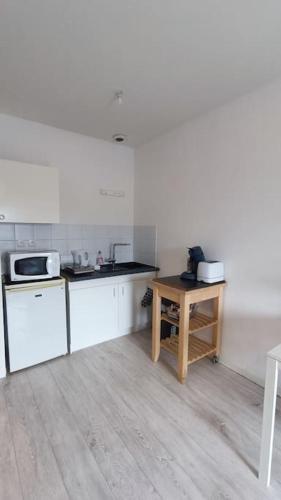 une cuisine avec comptoirs blancs et table en bois dans l'établissement Studio Centre Gare, à La Roche-sur-Yon