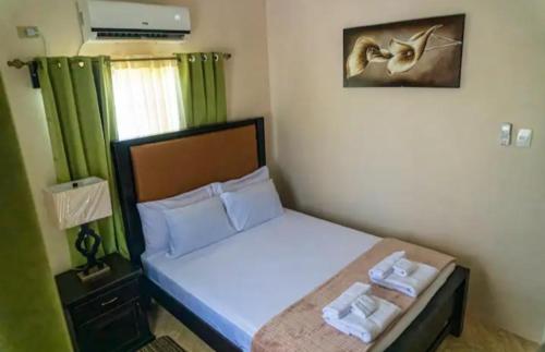 a small bedroom with a bed and a green curtain at Casa De Llewellyn's Apartments in Kelly Village