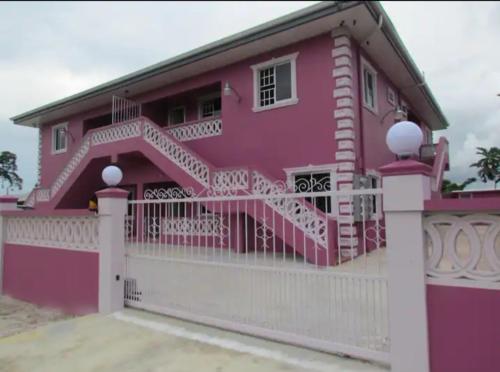 a pink house with a white fence at Casa De Llewellyn's Apartments in Kelly Village