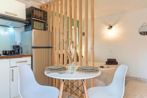 une cuisine avec une table et deux chaises blanches dans l'établissement Le Nid Eucalyptus, à Brive-la-Gaillarde