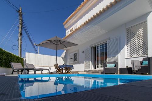 a house with a swimming pool and an umbrella at Villa Penedo in São Domingos de Rana