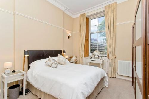 a bedroom with a large white bed and a window at Stylish Murrayfield sanctuary in Edinburgh