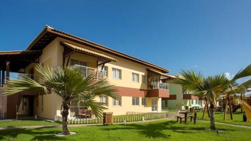 a building with palm trees in front of it at Apartamento em condomínio com passeio incluso in Baixio