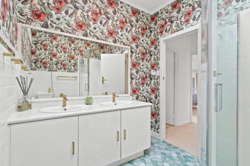 a bathroom with two sinks and a floral wallpaper at King Tide in Ballina