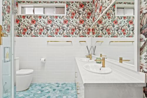 a bathroom with two sinks and a floral wallpaper at King Tide in Ballina