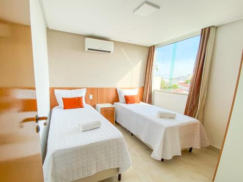 two beds in a room with a window at Ap 2 quartos espaçoso in Natal
