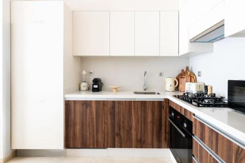 a kitchen with white cabinets and wooden counters at Luxury Eagle Hills Apartment in Rabat