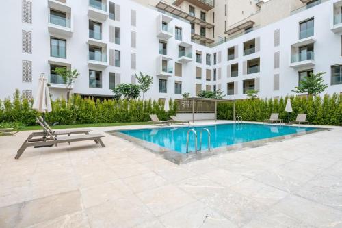 a swimming pool with a bench and a chair and a building at Luxury Eagle Hills Apartment in Rabat