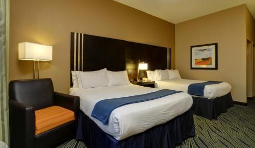 a hotel room with two beds and a chair at Holiday Inn Express & Suites Midwest City by IHG in Midwest City