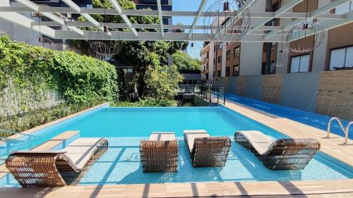 Una piscina con tumbonas y un hotel. en Lucas by Yoo por LikeHome, en Auxiliadora