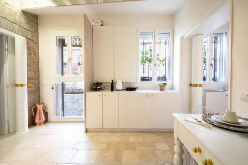 a kitchen with white cabinets and windows at Lemon House in Venice