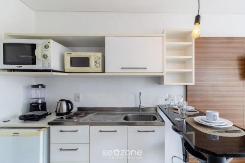 a small kitchen with a sink and a microwave at SPT - Studios Convenientes em Blumenau/SC in Blumenau