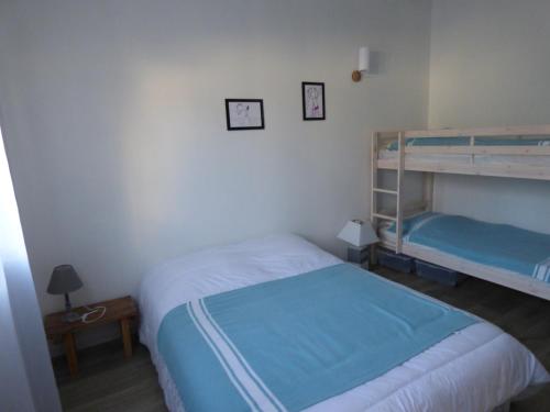 ein Schlafzimmer mit zwei Etagenbetten und einem Tisch in der Unterkunft Maison à 100 m de la plage, port et commerces à pieds -Les gîtes de Rhuys in Sarzeau