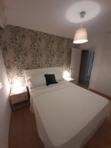 ein Schlafzimmer mit einem großen weißen Bett und einem grünen Kissen in der Unterkunft Cuesta del Tajillo in Torremolinos