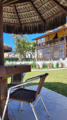 a table and chairs under a straw umbrella at Apart Hotel Beira do Mar in Florianópolis
