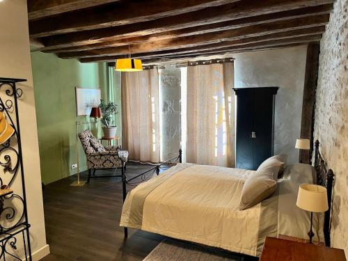 une chambre avec un grand lit et une chaise dans l'établissement Chez Jeannette, à La Charité-sur-Loire