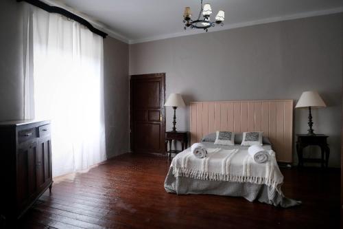 a bedroom with a bed and a large window at CASA RURAL PALACIO CONDE DE ALDANA con piscina entre encinares y dehesas in Terradillos