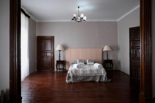 a bedroom with a bed and a chandelier at CASA RURAL PALACIO CONDE DE ALDANA con piscina entre encinares y dehesas in Terradillos