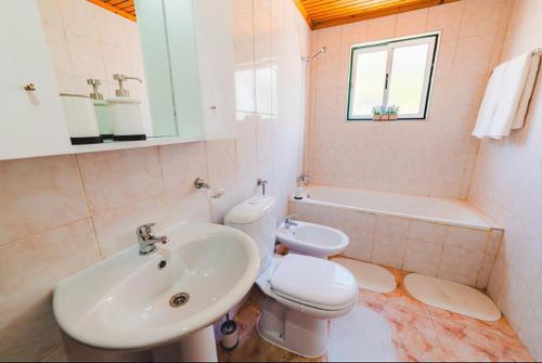 a bathroom with a sink and a toilet and a bath tub at Guest House Genuíno in Horta