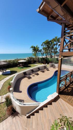 a swimming pool with chairs and the ocean in the background at Apart Hotel Beira do Mar in Florianópolis